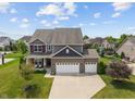 Aerial view of a beautiful home with a three-car garage, manicured lawn, and surrounded by lush greenery at 3679 Woodruff Pl, Bargersville, IN 46106