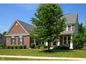 Beautiful two-story brick home with lush green lawn, mature landscaping and inviting front porch at 3853 Abney Highland Dr, Zionsville, IN 46077
