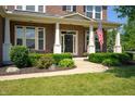Inviting front porch with classic columns, a black front door, and charming landscaping at 3853 Abney Highland Dr, Zionsville, IN 46077