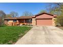 Charming single-story home with an attached garage, well-kept lawn, and a inviting orange front door at 40 S Restin Rd, Greenwood, IN 46142