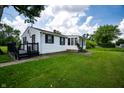 Charming home with a black deck and vinyl siding, surrounded by lush green lawn and mature trees at 4639 Terrace Ave, Indianapolis, IN 46203