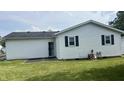 The rear exterior of this home features a well-maintained lawn and an access door at 6408 W Taylor Rd, Muncie, IN 47304