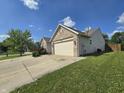 View of the brick home with an attached two-car garage and a well maintained lawn at 8460 Ferguson Cir, Avon, IN 46123
