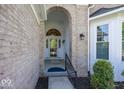Close-up of a brick home's entrance showcasing an arched doorway and manicured landscaping at 13161 Duval Dr, Fishers, IN 46037