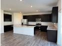 Modern kitchen boasts sleek dark cabinets, stainless steel appliances, and a large island with a white countertop at 210 Ames Dr, Whiteland, IN 46184