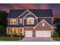 Charming two-story home with brick and blue facade, enhanced by warm lighting and a well-maintained lawn at 2245 Meadow Crk, Avon, IN 46123