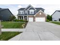 Well-manicured lawn and long driveway leading to a two-story blue and brick home with an attached two-car garage at 2245 Meadow Crk, Avon, IN 46123