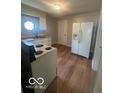 The kitchen features white appliances and wood look floors at 3026 S Rybolt Ave, Indianapolis, IN 46241