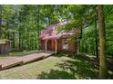 A cozy log cabin nestled in the trees with a red metal roof and wooden walkway at 3715 Orchard Rd, Columbus, IN 47201