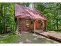 Quaint log cabin with a red metal roof and a small porch entrance in a wooded setting at 3715 Orchard Rd, Columbus, IN 47201