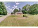Spacious home featuring a detached garage and a long driveway, surrounded by lush greenery at 5226 W Southport Rd, Indianapolis, IN 46221