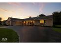Dusk view of gray brick ranch home with inviting front porch and meticulous landscaping at 5850 E 54Th Pl, Indianapolis, IN 46226