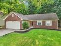 Inviting brick home with a two-car garage, neat landscaping, and a lush green lawn at 5935 Oakforge Ln, Indianapolis, IN 46254