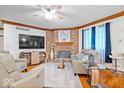 Cozy living room boasts a brick fireplace, ceiling fan, hardwood flooring and wainscotting at 7250 Royal Oakland Dr, Indianapolis, IN 46236
