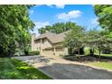 Spacious three-car garage with a long driveway and basketball hoop, surrounded by mature trees and lush greenery at 9690 Irishmans Run Ln, Zionsville, IN 46077