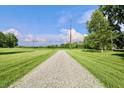 Long gravel driveway leading through the expansive grassy property under a clear blue sky at 3942 Senour Rd, Indianapolis, IN 46239
