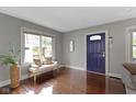Bright and welcoming living room featuring hardwood floors, large windows, and an inviting blue front door at 5209 E North St, Indianapolis, IN 46219