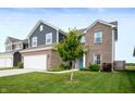 Two-story home featuring a brick-and-blue exterior, a two-car garage, and a tree in the front yard at 77 Winding Brook Way, Pendleton, IN 46064