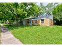 Inviting brick home on a lush green lawn with mature trees and an attached garage at 8540 E 37Th Pl, Indianapolis, IN 46226