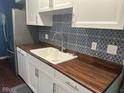 Updated kitchen boasts white cabinetry, wood countertops, stainless steel appliances, and patterned backsplash at 8540 E 37Th Pl, Indianapolis, IN 46226