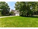 Spacious lawn leads to a home with a large driveway and three-car garage, surrounded by lush trees at 908 Queensbury Dr, Noblesville, IN 46062