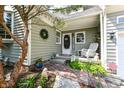 Cozy front porch with a brick walkway, decorated with a wreath, rocking chair, and potted plants at 908 Queensbury Dr, Noblesville, IN 46062