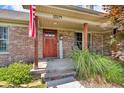 Covered front porch with brick facade, wooden support posts, and steps leading to the front door at 10174 N County Road 471 E, Pittsboro, IN 46167
