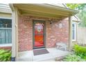 Close-up of the brick home's front entrance with a red door, small bench, and tidy landscaping at 11624 Buttonwood Dr, Carmel, IN 46033