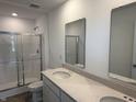 Bathroom featuring double sinks, a large mirror, a glass-enclosed shower, and modern fixtures at 1436 Aster Dr, Shelbyville, IN 46176