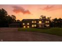 Two-story home exterior at sunset, warmly lit windows, and a three-car garage at 2227 Hidden Orchard Ct, Indianapolis, IN 46228