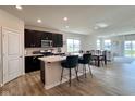 Open kitchen featuring an island with seating, dark cabinetry, stainless steel appliances, and light wood flooring at 2232 Warbler St, Danville, IN 46122