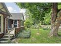 Side view of a bungalow with a brick exterior, fenced yard and mature tree at 4901 N Kenwood Ave, Indianapolis, IN 46208