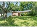 Quaint single-Gathering home showcasing a brick facade, attached garage, green lawn, and mature trees at 5530 Pilgrim Dr, Indianapolis, IN 46254