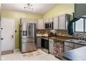 Galley kitchen featuring stainless steel appliances, tiled backsplash, and painted gray cabinets at 5530 Pilgrim Dr, Indianapolis, IN 46254