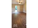Bright living room featuring wood-look floors, a ceiling fan, and sliding glass doors leading to the backyard at 5851 Brobeck Ln, Indianapolis, IN 46254