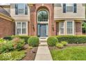 Close up view of a home's stately brick facade, arched entryway, and well-kept landscaping at 5865 Osage Dr, Carmel, IN 46033