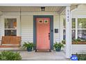 Close up of charming porch with a porch swing, house number, and coral front door with plants at 6142 Evanston Ave, Indianapolis, IN 46220