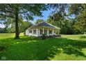 Quaint home featuring a charming covered front porch, inviting landscaping, and a well-manicured lawn at 6208 S 200 W, Trafalgar, IN 46181