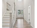 Bright foyer featuring wood-look floors, white stairs, and a front door with sidelights bringing in natural light at 6553 Stone Pointe Way, Indianapolis, IN 46237