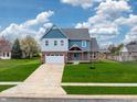 Beautiful two-story home with brick and light blue accents, set on a lush green lawn at 7604 Brownstone Ct, Greenfield, IN 46140