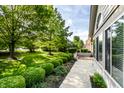Expansive lawn with mature trees and green bushes surrounding a well-maintained home and walkway at 7919 Cool Hollow Pl, Indianapolis, IN 46237