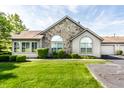 Traditional home showcasing stone accents, a well-maintained lawn, and a paved driveway to the garage at 7919 Cool Hollow Pl, Indianapolis, IN 46237