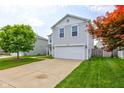Inviting two-story home featuring light gray siding, a spacious two-car garage, and well-maintained front yard with mature trees at 9593 W Constellation Dr, Pendleton, IN 46064
