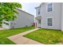 View of the side yard with lush green grass, a paved walkway, and light gray siding leading to the front door at 9593 W Constellation Dr, Pendleton, IN 46064