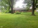 Charming single-story brick home on a lush, green lawn with mature trees providing shade at 106 N 300 W, Greenfield, IN 46140
