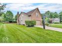 Side view of home featuring manicured lawn, trees, and basketball hoop at 11123 Garrick St, Fishers, IN 46038