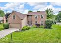Inviting two-story brick home featuring a well-maintained lawn and lush landscaping at 11123 Garrick St, Fishers, IN 46038