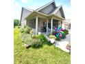 Attractive home featuring a cozy, covered porch with colorful flowers and beautifully landscaped garden at 1688 Magnolia Dr, Greenwood, IN 46143