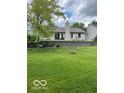 Spacious backyard with lush green grass, a retaining wall, mature trees, and a charming firepit at 17717 Cedarbrook Dr, Westfield, IN 46074