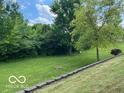 Picturesque backyard featuring a retaining wall, mature trees and lush greenery perfect for outdoor enjoyment at 17717 Cedarbrook Dr, Westfield, IN 46074